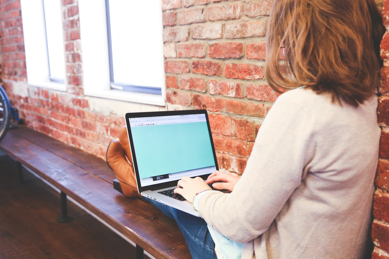 Femme sur un banc en train de consulter un ordinateur portable